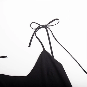 Detail of adjustable black cotton shoulder straps tied in a bow on an open back dress