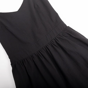 Close-up of black cotton V-neck dress featuring high waist pleats and detailed stitching