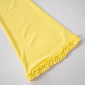 Detail of bright yellow ruffled hem showing fine knit texture on an off-shoulder dress
