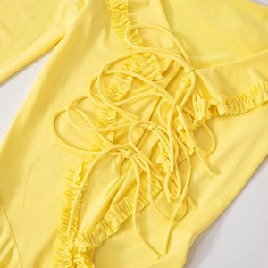 Detailed macro view of yellow ruffles and intricate lace-up drawstring on the dress