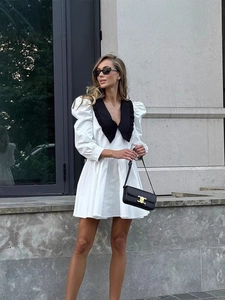 Short A-line dress with black Peter Pan collar and white puff sleeves in outdoor setting