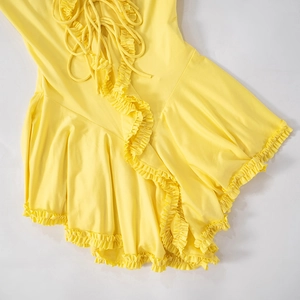 Detailed view of yellow dress with cross-tie laces and delicate ruffle hem textures