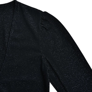 Détail de la robe noire à col en V profond avec lurex argenté scintillant et manches bouffantes