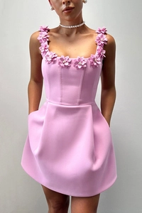 Détails des appliques florales roses sur l'encolure et les bretelles d'une robe mini