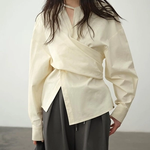 Detail der cremeweißen Wickelbluse mit asymmetrischen Falten und Ausschnitt-Detail