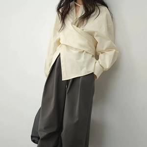 Detail der Wickelbluse mit langen Ärmeln, tailliertem Design und Faltenakzent