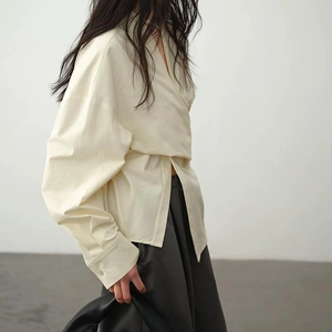 Seitenansicht der beigen Wickelbluse mit tiefem V-Ausschnitt und asymmetrischer Taille
