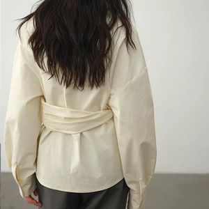 Rückansicht der beige Wickelbluse mit verstellbarer Taillenbindung und tiefen Schultern