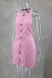 Detail of pink halter dress featuring eight golden rose-shaped buttons on textured fabric