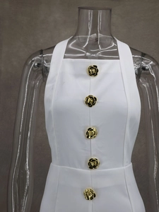 Close-up of white halter dress featuring gold-edged black camellia decorative buttons
