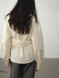 Schicke cremefarbene asymmetrische Bluse mit Bindegürtel und elegantem Rückendetail