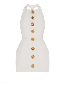 Detailed view of white halter neck dress featuring golden rose-shaped metal buttons