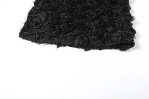 Detail von 3D-Stoff mit dichten schwarzen Rosen auf einem schicken Bodycon-Rock