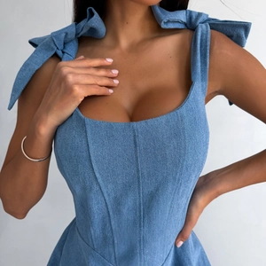 Detail van blauwe denim jurk met decoratieve strikbandjes en gestructureerd lijfje