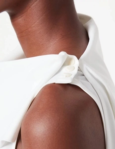 Détail d'un top sans manches blanc en mousseline avec encolure asymétrique et boutons d'épaule