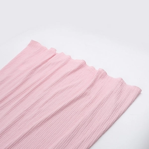 Close-up of light pink pleated fabric texture with fine vertical accordion pleats
