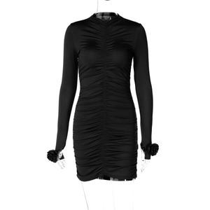 Détail d'une robe noire plissée à manches longues avec des roses 3D ornées aux poignets