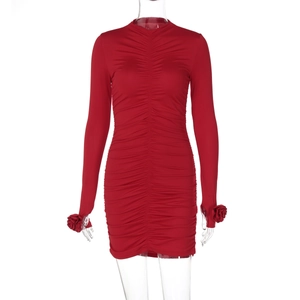 Détail de la robe rouge à manches longues avec fronces et fleurs 3D sur les poignets