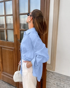 Detail of light blue linen shirt featuring a relaxed collar and breathable fabric texture