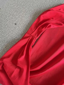 Détail de la robe licou rouge avec tissu côtelé texturé et design plissé torsadé