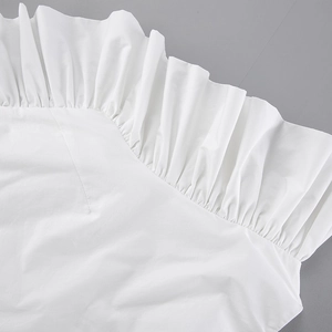 Detailed close-up of white cotton fabric featuring elegant ruffled edge and layered pleats