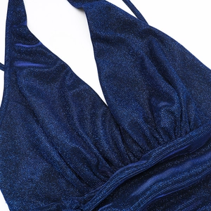 Macro detail of dark blue sparkly fabric with deep V-neckline and halter design