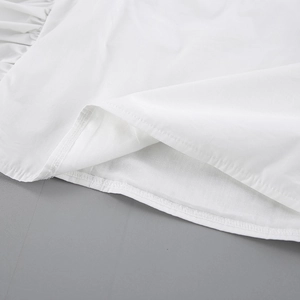 Detail of white cotton blouse showing fine stitching and gathered ruffle hem design