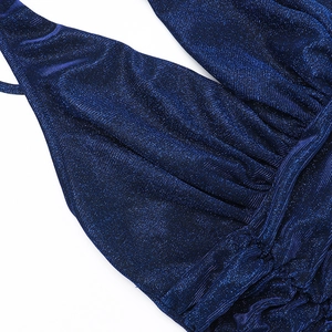 Macro view of dark blue glitter fabric with pleated details on a deep V-neck dress