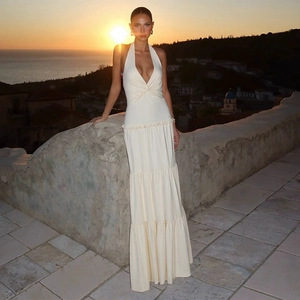 Detail of deep V-neck and twist knot design on a beige backless halter maxi dress