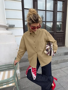 Detail of khaki cotton utility shirt with front pocket, sunglasses, and polka dot scarf