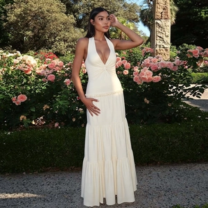 Detail of elegant cream halter neck maxi dress with tiered ruffle skirt and v-neckline