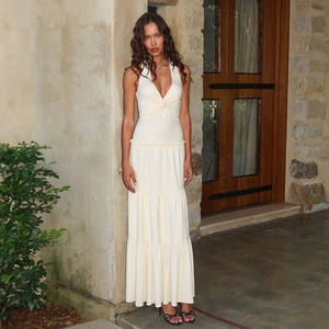 Detail of deep V-neck and tiered skirt design on a cream halter maxi dress