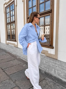 Light blue linen long sleeve shirt paired with white wide leg pants in street style