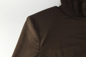 Détail de la couture du col montant et des épaulettes d'une robe marron foncé ajustée