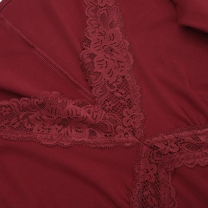 Detailed close-up of intricate lace trim and V-neckline on burgundy knit dress