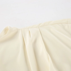 Detailed view of sophisticated pleated neckline on a creamy chiffon blouse for women