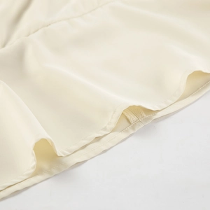 Macro detail showing smooth hem stitching and apricot chiffon fabric texture of the blouse