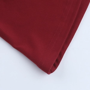 Detailed close-up of double-stitched hem and fine knit texture on dark red dress sleeve