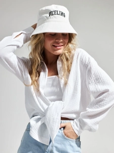 Detail view of white cotton crepe shirt with knot hem and feeling slogan bucket hat
