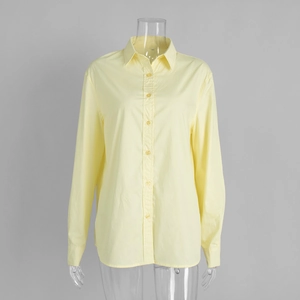 Detail view of a pale yellow cotton shirt showing lapel collar and button closure