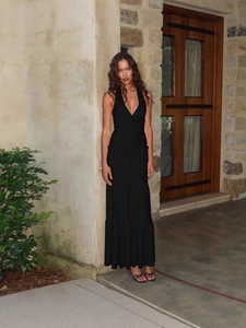 Elegant black halter maxi dress with deep V-neck and tiered skirt in a chic summer style