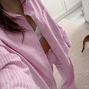 Detail view of pink and white vertical striped pajamas shirt and loose trousers