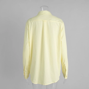 Macro view of back pleat detail and sleeve cuff on a yellow cotton long sleeve shirt