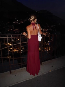 Elegant burgundy halter backless maxi dress with tiered skirt in urban night setting
