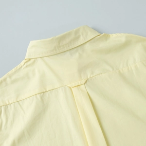 Detailed back view of a yellow cotton shirt showing the yoke and central pleat detail