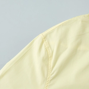 Detailed close-up showing stitching craft on yellow cotton shirt shoulder and sleeve seams