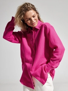 Close-up of the breathable cotton crepe fabric texture on a fuchsia women's polo shirt