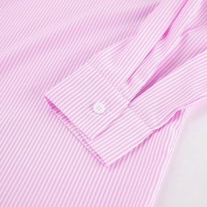 Macro detail of pink striped shirt cuff featuring a fine white button and cotton texture