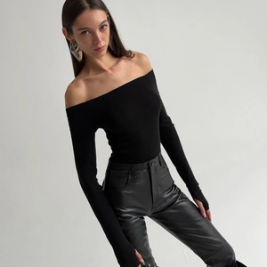 Detail of a slim-fit black off-the-shoulder long sleeve top with ribbed stretch fabric