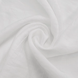 Macro shot of white textured fabric showing delicate weave and soft ruffled layers